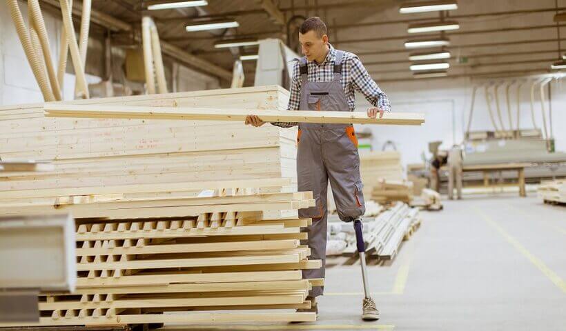 man with prosthetic leg sorting wood in a woodworking shop