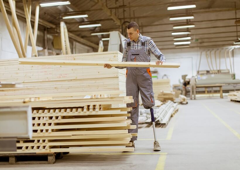 man with prosthetic leg sorting wood in a woodworking shop