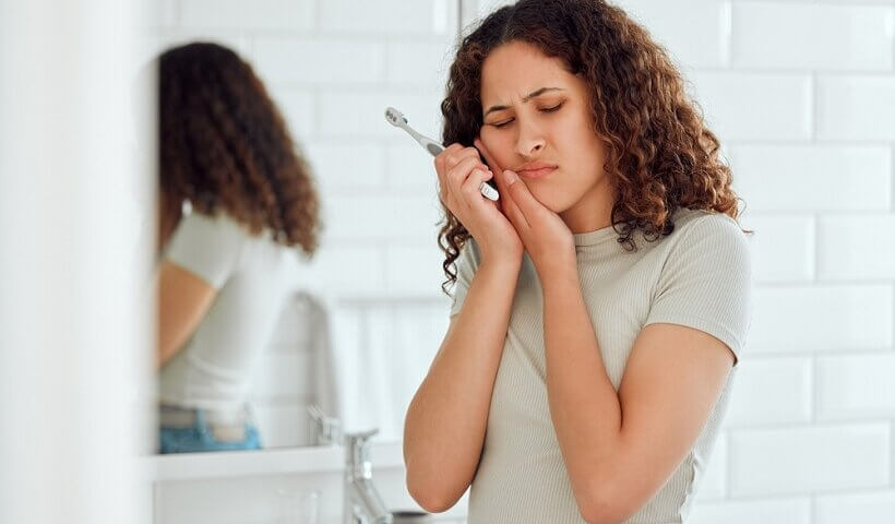 woman holding the side of her face experiencing dental pain.