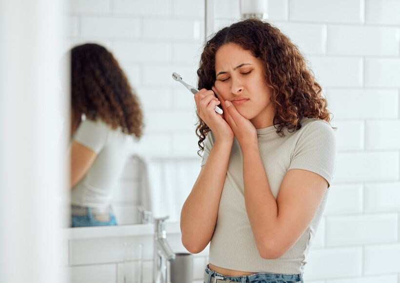 woman holding the side of her face experiencing dental pain.